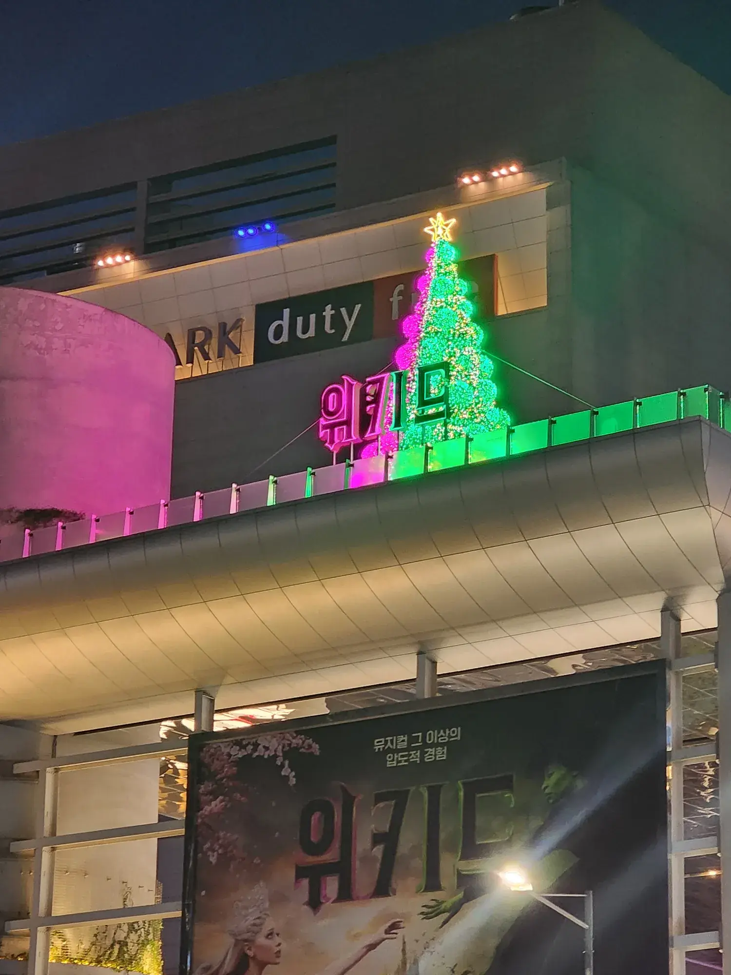 용산 아이파크몰 〈위키드〉 홍보 트리 — 면세점 옥상 위 트리와 대형 현수막